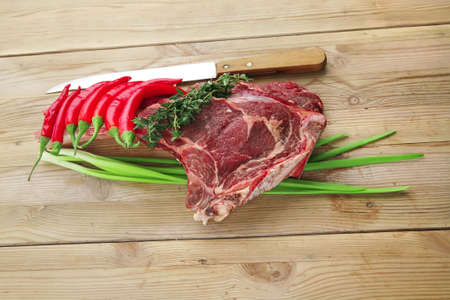 raw meat : boned fresh lamb ribs served with thyme , red chili pepper , and green onion on wooden...