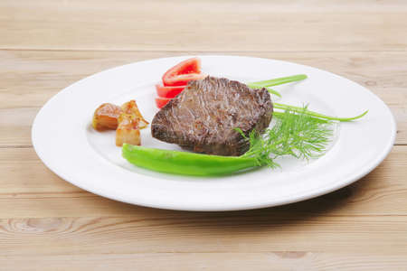 meat food : roast beef fillet mignon served on white plate with apples dill and tomatoes over wooden tableの写真素材