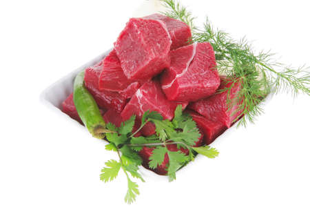 uncooked fresh beef meat chunks on white bowls with green hot peppers and vegetables isolated over...