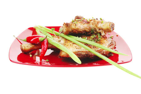savory food : roasted chicken legs garnished with green sprouts and peppers on red plate isolated over white backgroundの写真素材