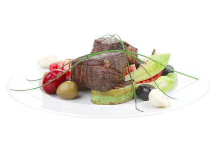 savory food : roast beef garnished with baked apples , green and black olives on white plate isolated over white backgroundの写真素材