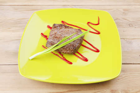 meat savory : grilled beef fillet mignon served on green plate over wooden table with chives and ketchupの写真素材