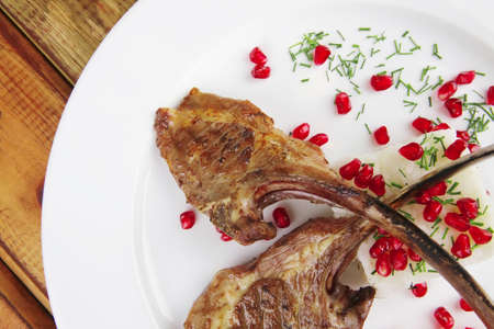 meat savory: roast veal ribs with rice garnish and pomegranate seeds on white over woodの写真素材