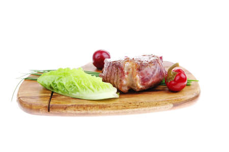 meat savory : beef fillet mignon grilled and garnished with green lettuce and red chili hot pepper on wooden plate isolated over white backgroundの写真素材