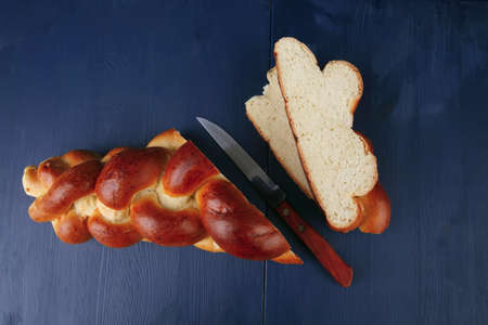 baked product : cutted golden challah on blue wooden table
