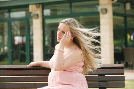 Beautiful blond pregnant woman relaxing on the bench . outdoor.の写真素材