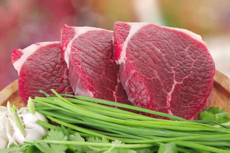fresh meat : raw uncooked fat lamb pork fillet with green stuff and garlic on wooden plate isolated...