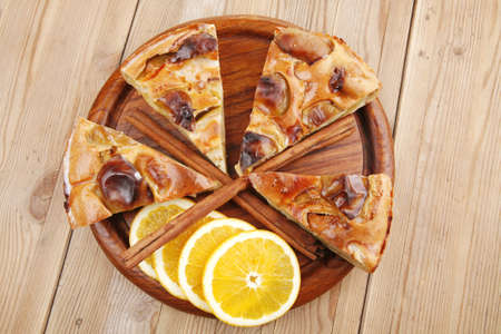 sweet food : cuts of apple pie on wooden plate with cinnamon sticks and lemonsの写真素材