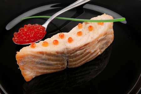 savory sea fish portion : roasted salmon fillet with green onion and red caviar in spoon on black dish isolated over white backgroundの写真素材