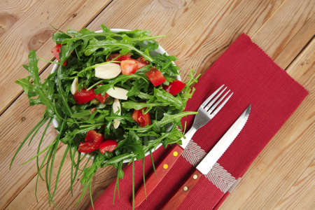 healthy appetizer : salad with raw tomato , garlic , and green staff in white bowl over wood served with cutleryの写真素材