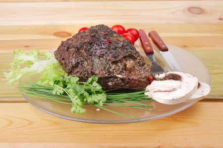 beef on transparent plate with vegetables over woodの写真素材