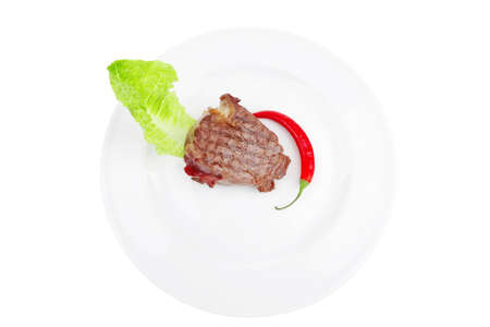 barbecued meat : beef ( lamb ) garnished with green lettuce and red chili hot pepper on white plate isolated over white backgroundの写真素材