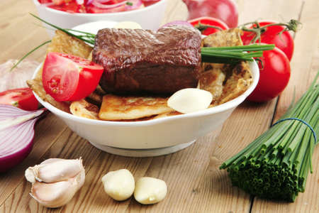 meat : grilled beef fillet mignon on bread with tomatoes salad on wooden table