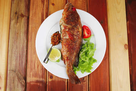 main portion of two grilled fish served on plate with tomatoes and spicesの写真素材