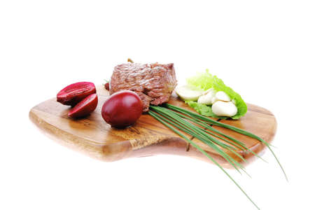 barbecued meat : beef ( lamb ) garnished with green lettuce and red chili hot pepper on wooden plate isolated over white backgroundの写真素材
