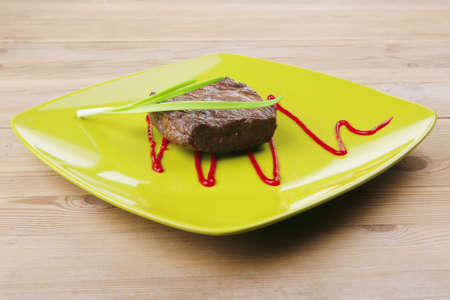 meat food : roasted fillet mignon on green plate with chives and ketchup over wooden tableの写真素材