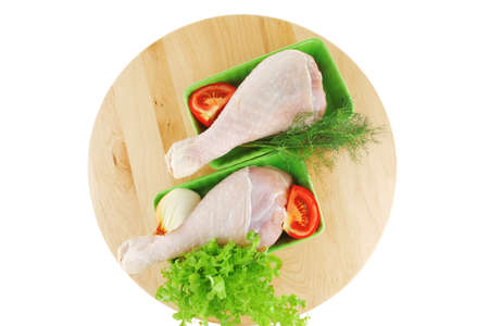raw chicken drumstick on wooden plate on whiteの写真素材
