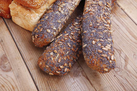 fresh mix of baguettes , pretzels and wheat bread, on wooden tableの写真素材