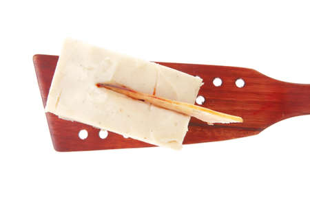 small cream cake on wooden spatula over white
