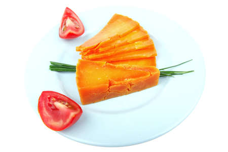 old delicious cheddar cheese chop with slice on blue plate with tomatoes and chives isolated over white backgroundの写真素材