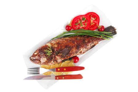 savory isolated on white: whole fryed sunfish over plate with tomatoes lemons and peppers