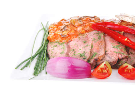 beef on plate with vegetables over white の写真素材