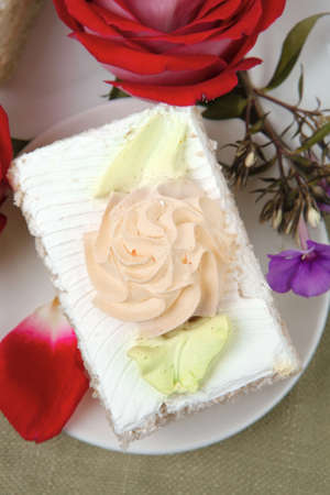 sweet food: cheese cream cake piece on white dish with rosesの写真素材