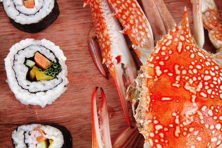 Maki Roll with Deep Fried Vegetables inside . on wooden plate with live crab . isolated over white background . Japanese Cuisine の写真素材