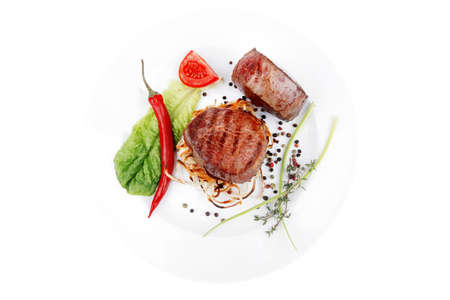 grilled beef fillet medallions with thyme and red hot chili pepper on plate isolated over white backgroundの写真素材