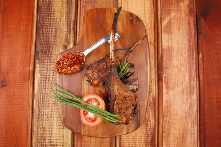 savory plate on wood : grilled ribs on plate with chives and tomato isolated on wooden table