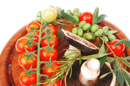 uncooked raw vegetables on wooden plate over whiteの写真素材