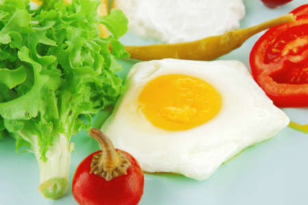 fried eggs with curd and salad on blue plateの写真素材