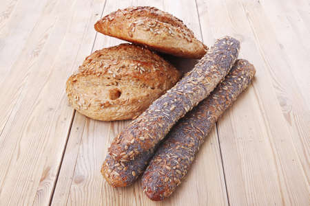 delicacy french rye breads and baguettes topped with sunflower and poppy seeds over wooden table
