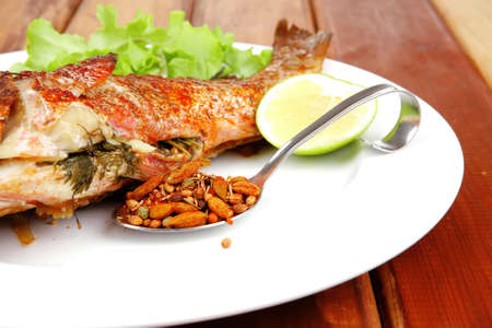 main portion of two grilled fish served on plate with tomatoes and spicesの写真素材