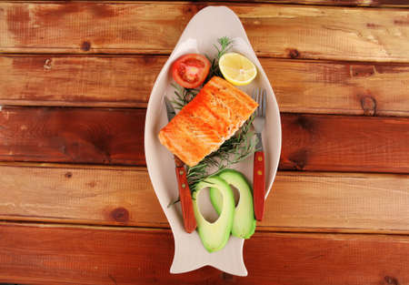 served fish: roast salmon fish over glass plate over woodの写真素材