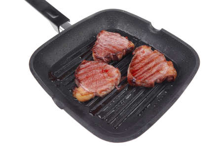 fresh grilled bloody beef steaks on black grill plate isolated on white backgroundの写真素材
