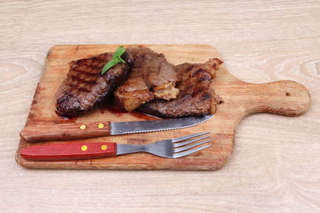 bbq beef meat fillet on wooden plate with cutleryの写真素材