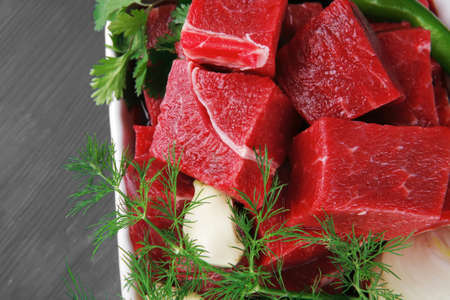 slices of raw fresh beef meat fillet in a white bowls with dill and green peppers serving over blue wooden tableの写真素材