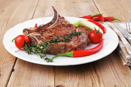 meat food : grilled beef spare rib on white dish with thyme pepper and tomato on wooden tableの写真素材