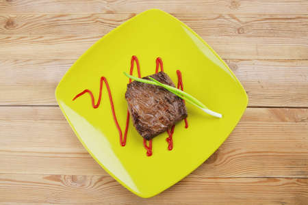 meat savory : grilled beef fillet mignon served on green plate over wooden table with chives and ketchupの写真素材
