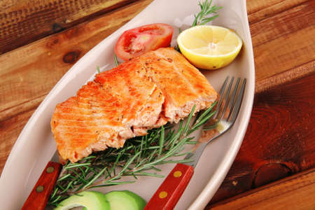 served fish: roast salmon fish over glass plate over woodの写真素材