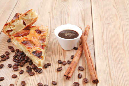 baked food: apple pie on wooden table served with coffee cup and cinnamon sticksの写真素材