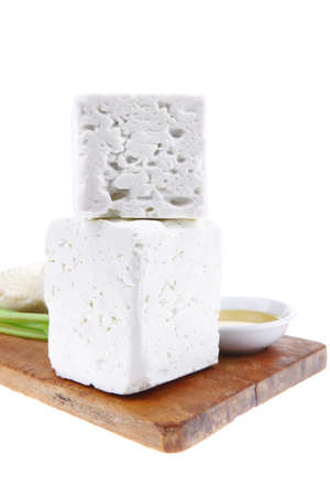 dairy product : fresh raw white soft greek feta cheese cubes and round on wooden plate isolated over white backgroundの写真素材