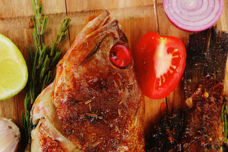main portion of two grilled fish served on wooden plate