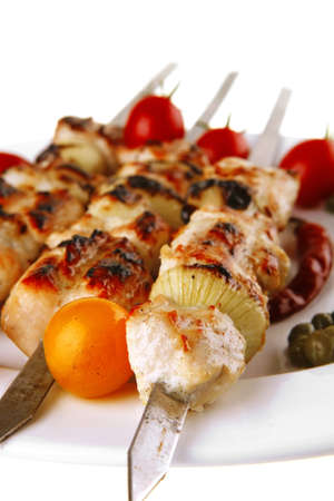 pork shish kebab on white platter with vegetablesの写真素材