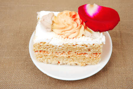 sweet food: cake with whipped cream served with roses on white saucer