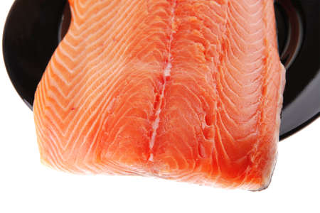 piece of salmon fillet on black plate over whiteの写真素材