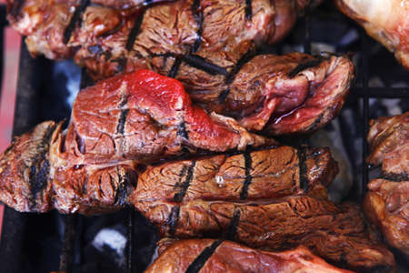 big beef steak on grilling grid over barbecue charcoalの写真素材
