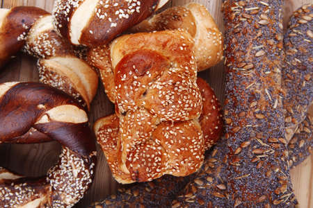 fresh mix of baguettes , pretzels and wheat bread, on wooden table