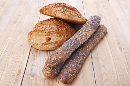 delicacy french rye breads and baguettes topped with sunflower and poppy seeds over wooden table